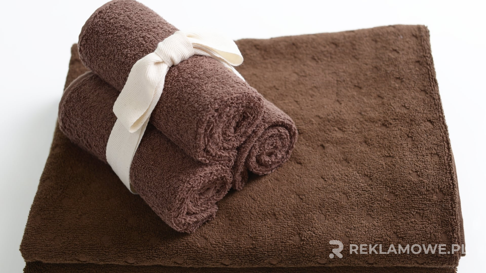 Stos różnokolorowych ręczników reklamowych